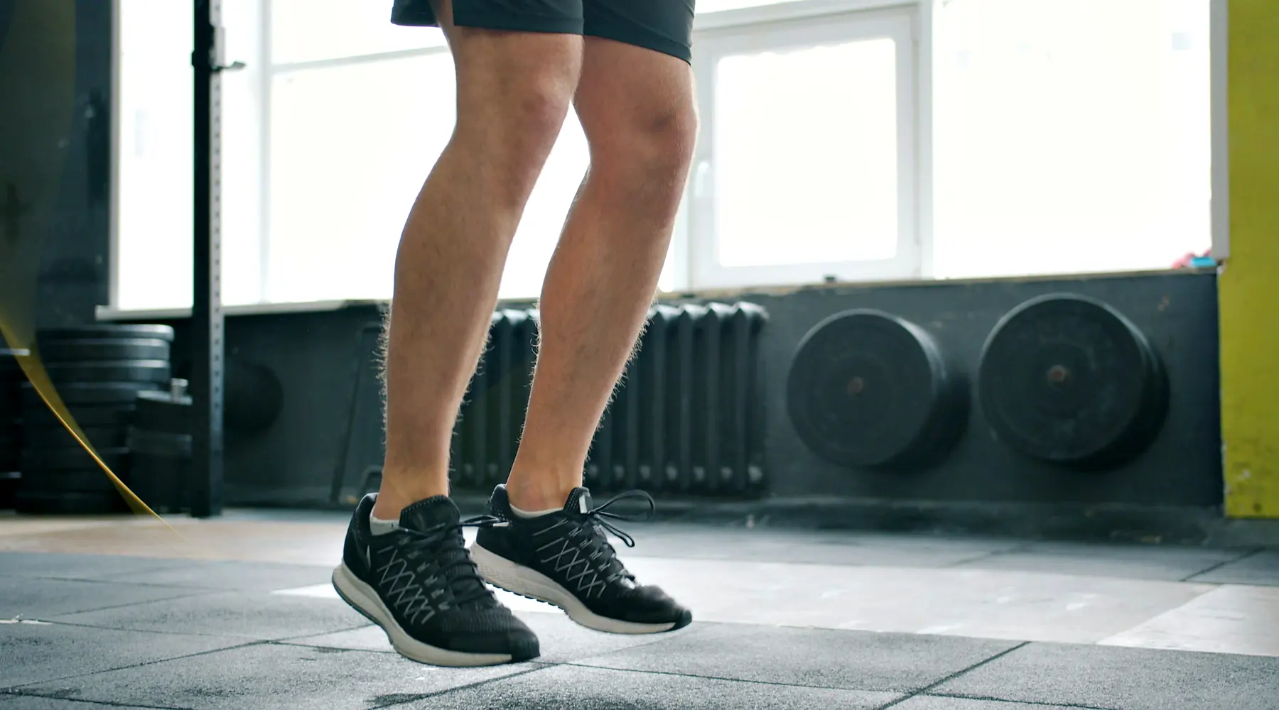 A close view of a lifter's legs mid-jump while skipping rope