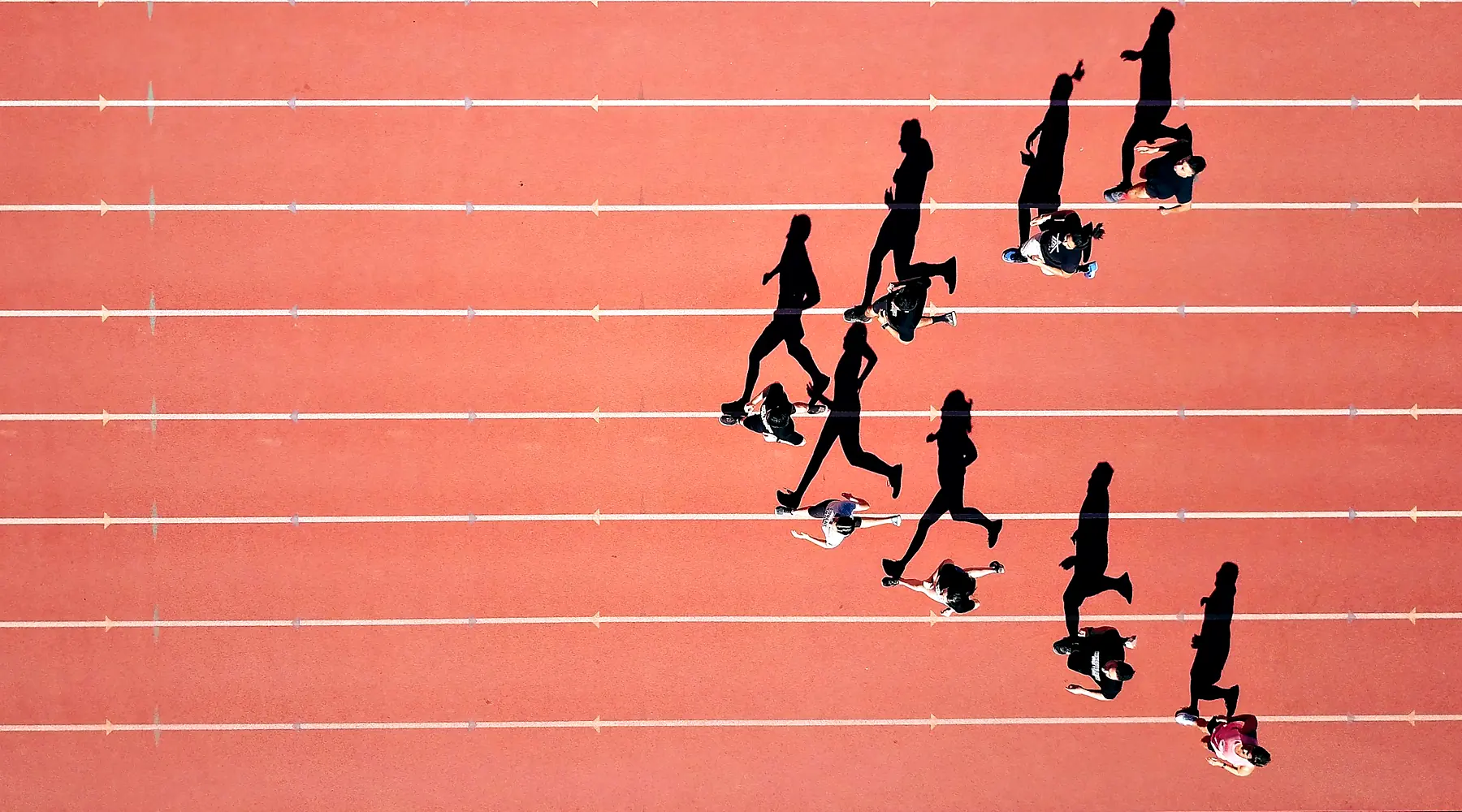 Runners sprint down the lanes of a track, seen from above