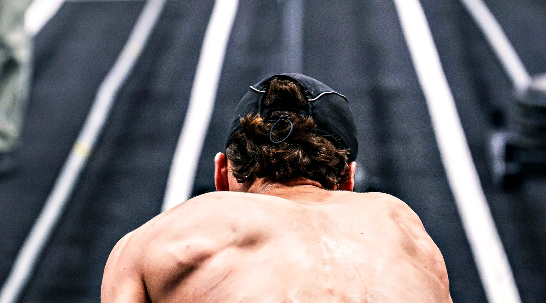 A lifter crouches at the end of a sled track, ready to push