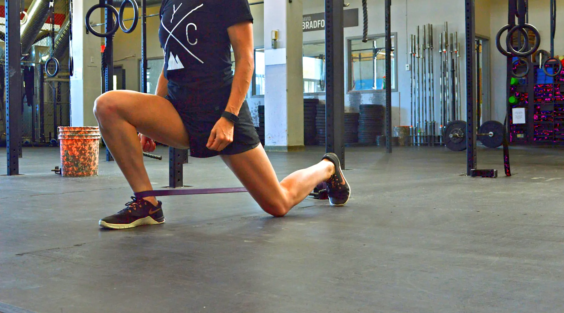 A woman lunges on a gym floor