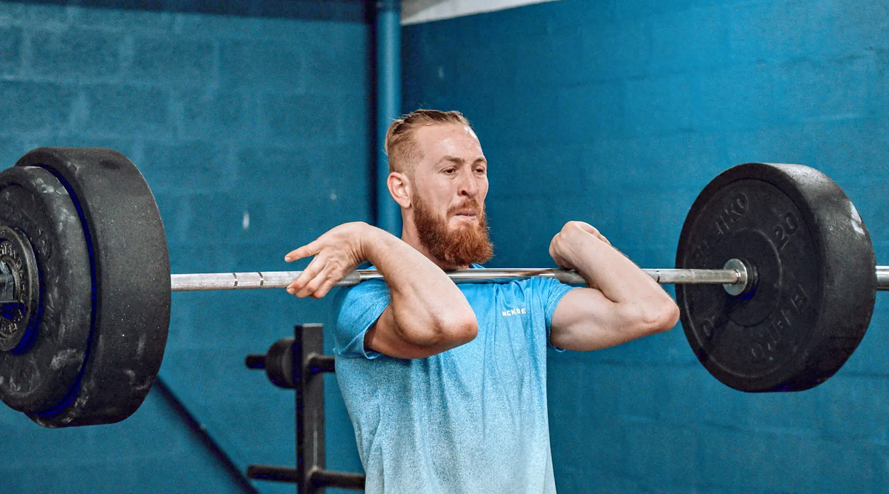 A man holds a barbell in the front rack before a front squat