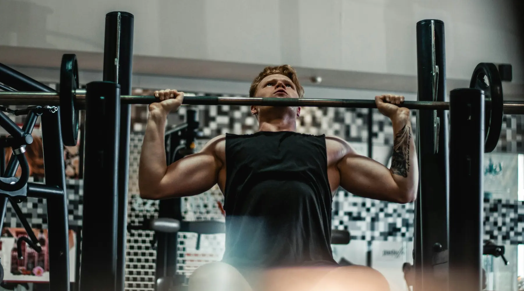 A lifter setting up under a loaded barbell at a rack