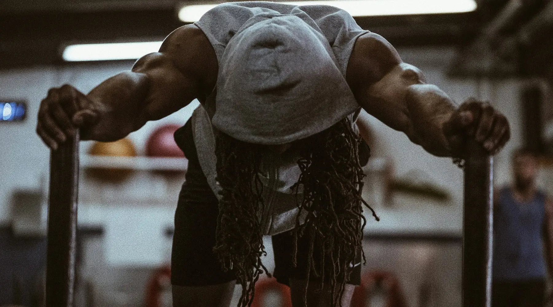 A lifter leaning on a rack between heavy sets, head down