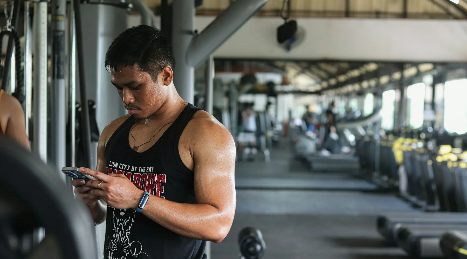 A lifter checking his phone between sets in a gym